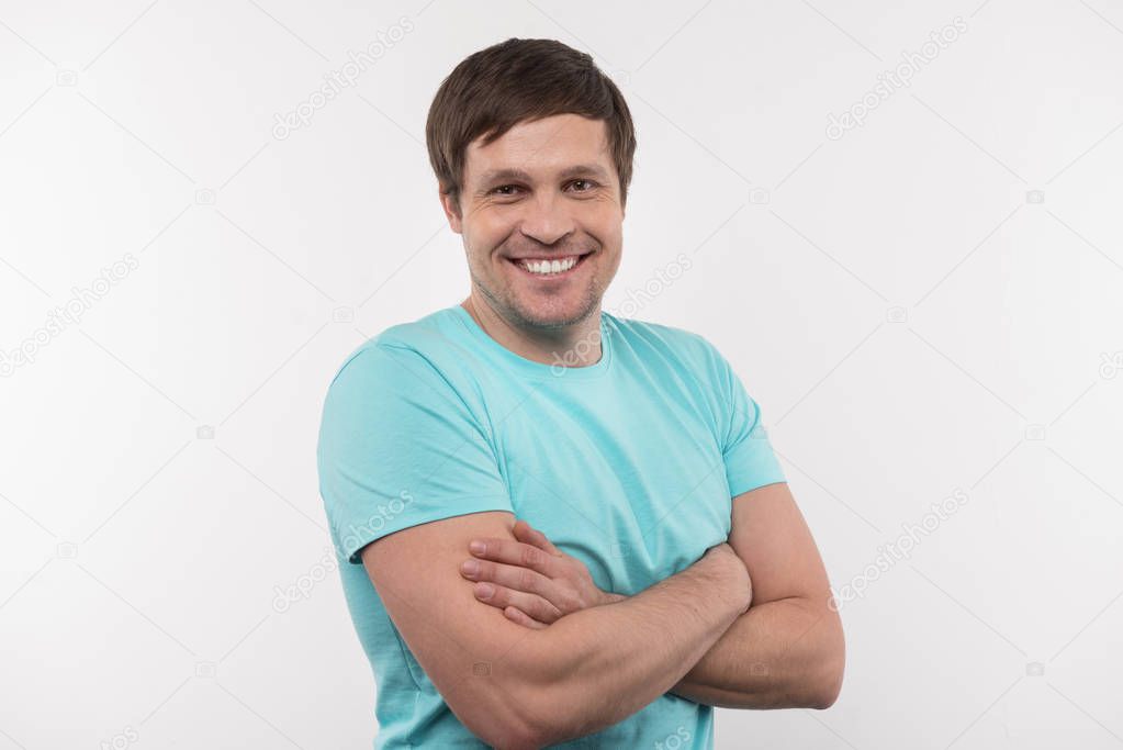 Positive delighted man standing with his arms crossed