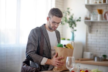 İş adamı eve yiyecek dolu bir çantayla dönüyor.