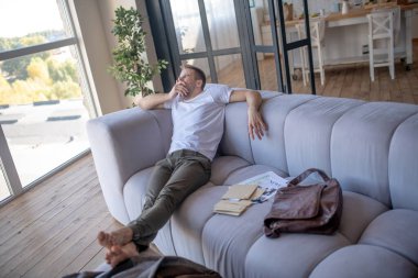 İş adamı kanepede oturuyor ve uykusunda esniyor.