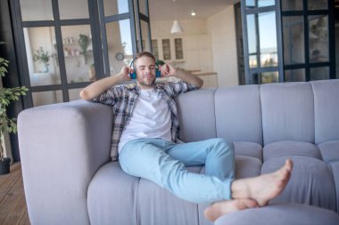 Yakışıklı adam en sevdiği şarkıyı dinlerken kareli gömlek giyiyor.