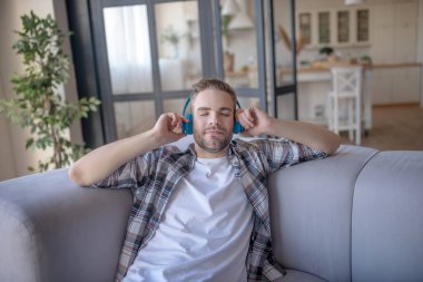 Sakallı adam şarkı söylerken gözlerini kapatıyor.