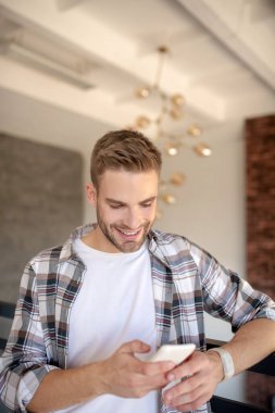 Kız arkadaşından mesaj okurken gülümseyen yakışıklı bir adam.