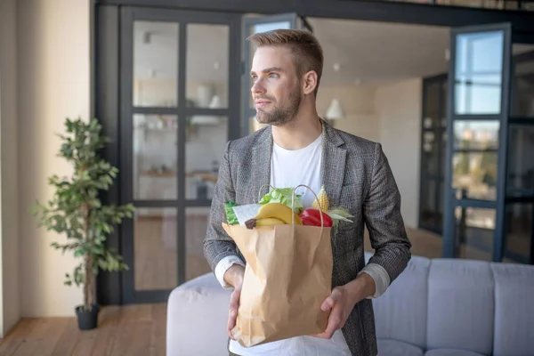 Blue-eyed young businessman holding bag after shopping