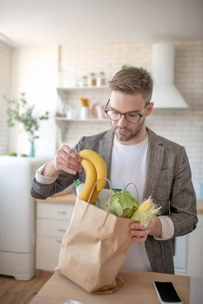 Hombre barbudo guapo sacando plátanos de la bolsa — Foto de Stock