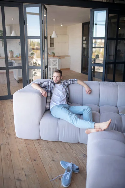 Barfota man kylning på soffan i vardagsrummet — Stockfoto