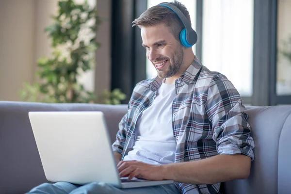 Homem alegre usando fones de ouvido assistindo filme no laptop — Fotografia de Stock