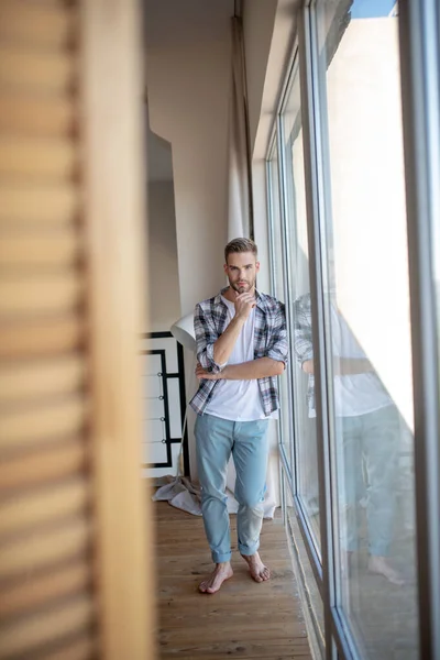 Beau homme portant un jean debout dans une pièce spacieuse et lumineuse — Photo