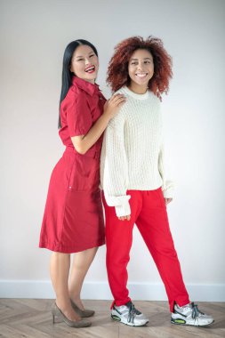 Duvarın yanında duran şık, parlak kıyafetler giyen arkadaşlar.