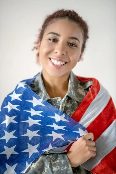 Jonge dienstvrouw draagt militaire vrouw met vlag — Stockfoto