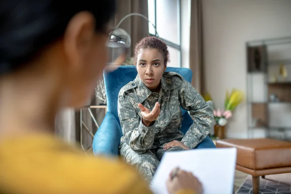 Dark-eyed young military woman explaining stressful moments