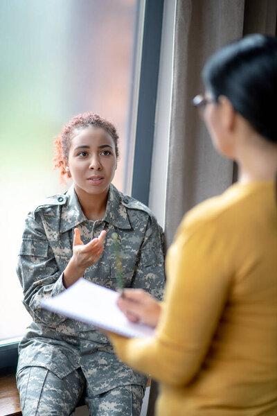 Young patriotic military woman speaking with psychologist