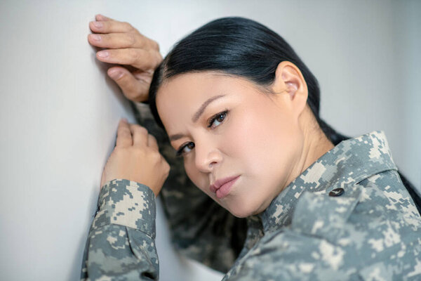 Dark-eyed Asian servicewoman feeling stressed and depressed