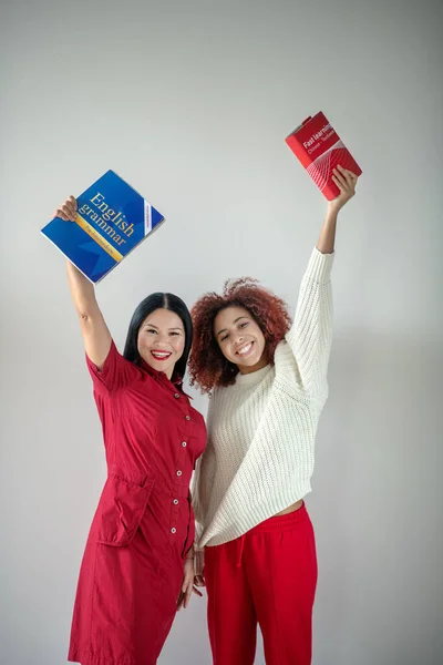 Amigos segurando livros ingleses perto da parede — Fotografia de Stock