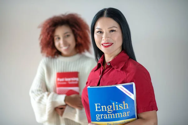 Mujer sosteniendo libro de gramática inglesa mientras estudia idiomas —  Fotos de Stock