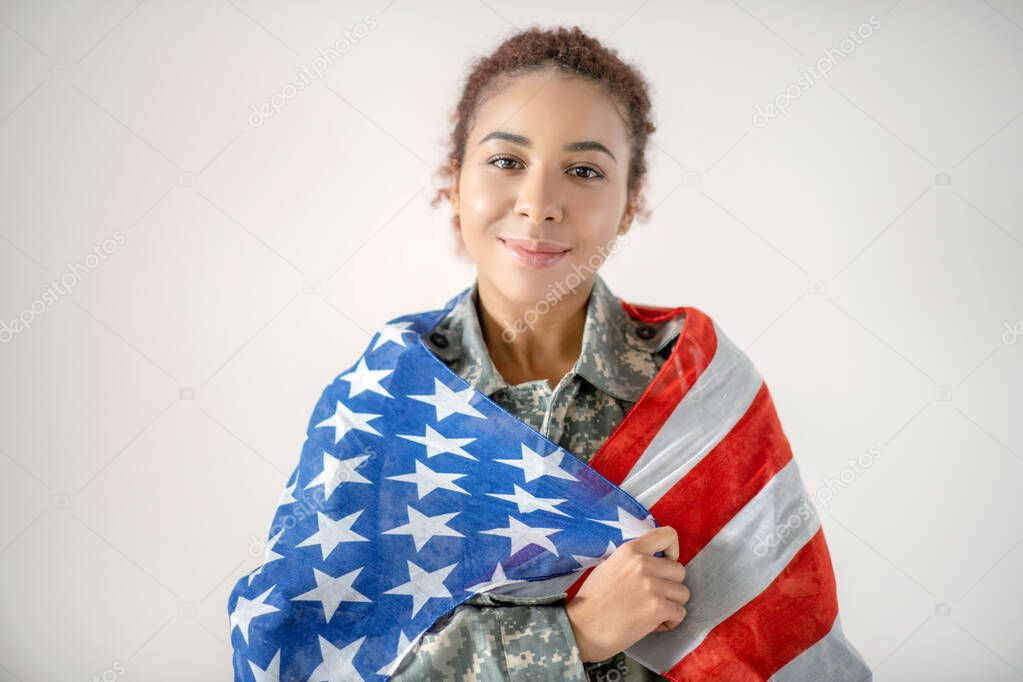 Beautiful young patriotic servicewoman holding American flag