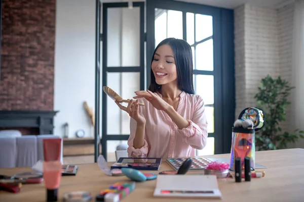 Mujer sonriente tomando polvo mientras comienza a maquillarse — Foto de Stock