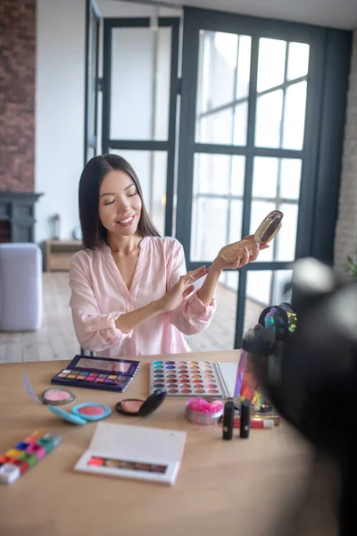 Blogger de belleza probando su nuevo colorete mientras hace maquillaje — Foto de Stock