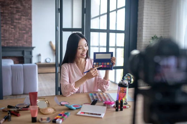 Beauty blogger taking brush before putting eyeshades on eyelids — Stock Photo, Image