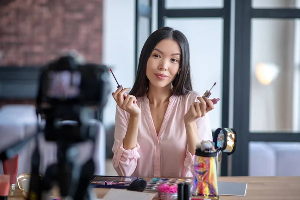 Primer plano del blogger de belleza mostrando dos colores favoritos de brillo labial — Foto de Stock