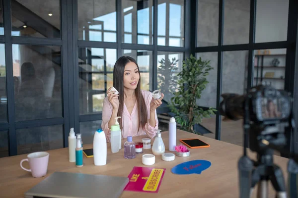 Koyu renk saçlı kadın blog çekerken krem tavsiye ediyor