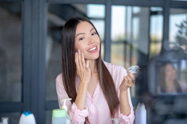 Smiling young beautiful woman applying moisturizing cream — Stock Photo, Image