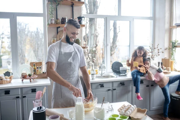 Vousatý muž v zástěře vařící koláč pro své dcery — Stock fotografie