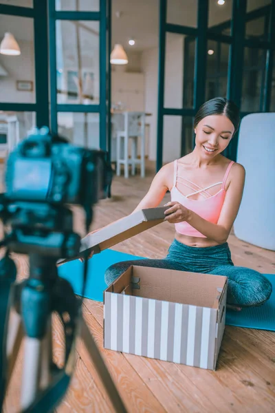 Gimnasio blogger sonriendo mientras abre caja con presente de seguidor — Foto de Stock