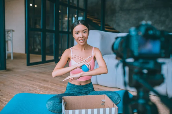 Slim fitness blogger filming video about massage ball