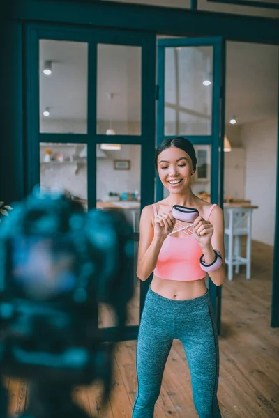 Koyu renk saçlı spor eğitmeni video çekerken pembe kol ağırlığını gösteriyor — Stok fotoğraf