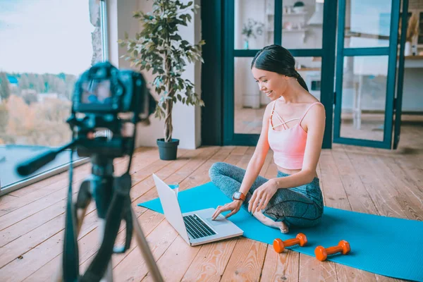 Blogger fitness usando su portátil mientras trabaja en un nuevo video — Foto de Stock