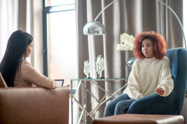 Geniş bir odada psikanalisti ziyaret eden genç bir kadın.