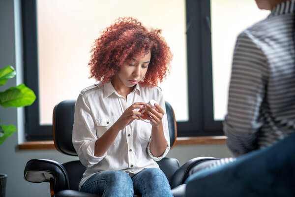 Curly young woman reading description of antidepressants