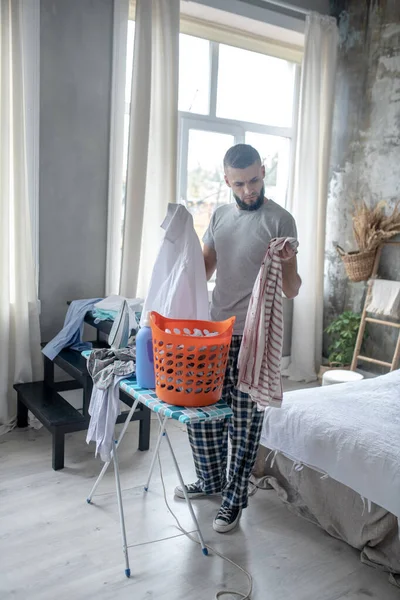 Bearded man preparing clothes for laundry at the weekend