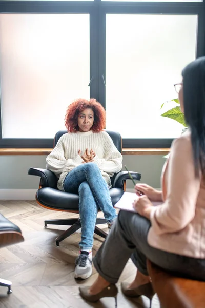 Mujer joven sentada cerca de la ventana y hablando con psicoanalista — Foto de Stock