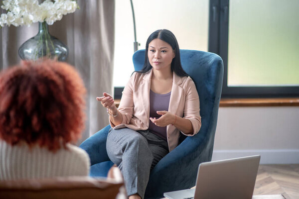 Asian professional female psychologist speaking with client