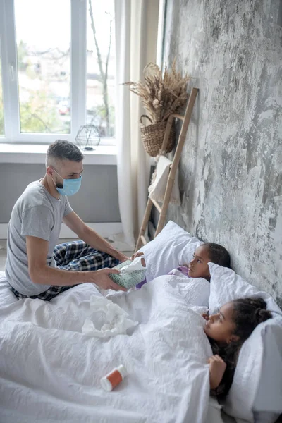 Far bär mask med servetter till sina sjuka döttrar — Stockfoto