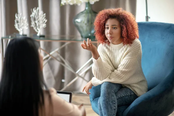 Young woman wearing jeans speaking with psychologist