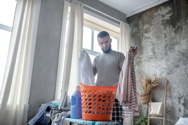 Hombre sintiéndose reflexivo al dividir la ropa antes de la lavandería — Foto de Stock