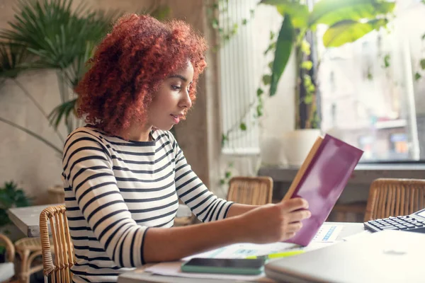 Roodharige jonge mooie zakenvrouw leest zakelijke literatuur — Stockfoto