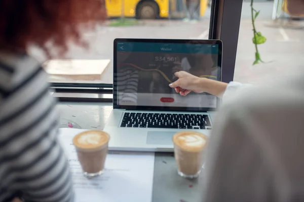 Vrouwen die cappuccino drinken en de wisselkoersen controleren — Stockfoto