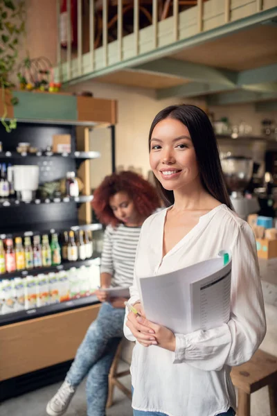 Mujer asiática propietaria de cafetería con amigo sosteniendo documentos — Foto de Stock