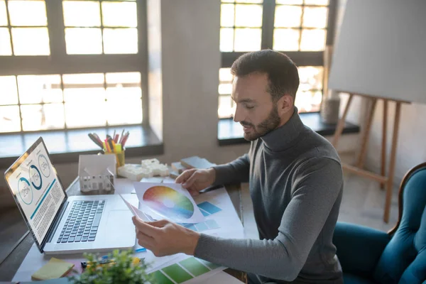 Inredningsdesigner sitter nära bärbar dator och tittar på färgpalett — Stockfoto