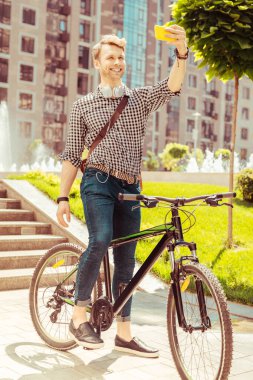 Neşeli genç adam akıllı telefonuna bakıyor.