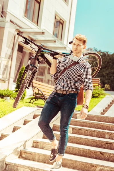 Attentif jeune homme tenant le vélo dans la main droite — Photo