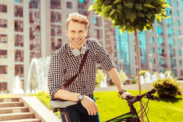 Fröhlicher junger Mann lehnt auf seinem Fahrrad — Stockfoto