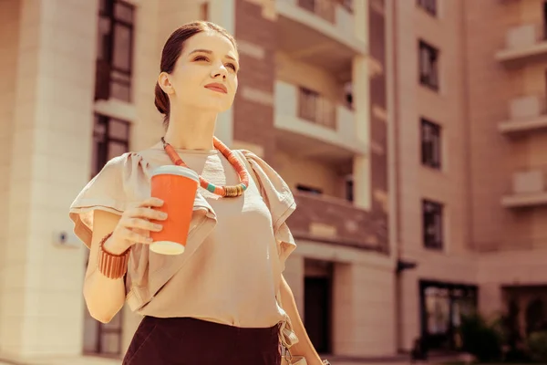 Jeune femme rêveuse dégustant un café savoureux pendant la promenade — Photo