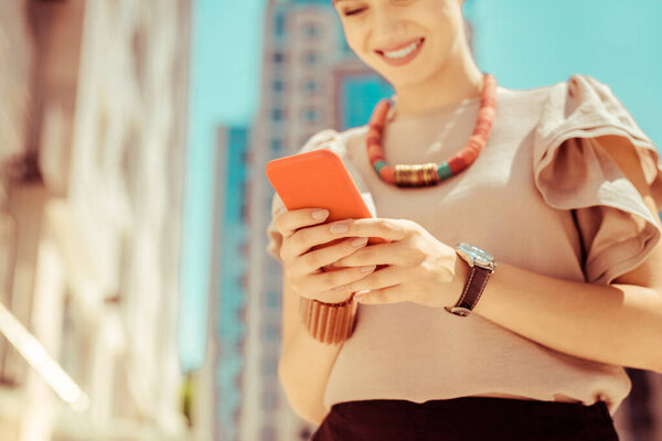 Сфокусированное фото на женских руках, которые держат смартфон
