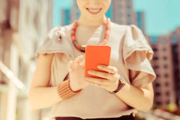 Радостная молодая женщина, печатающая сообщение своей подруге
