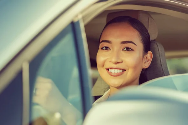 Cheerful brunette girl sitting in her car — Stock Photo, Image