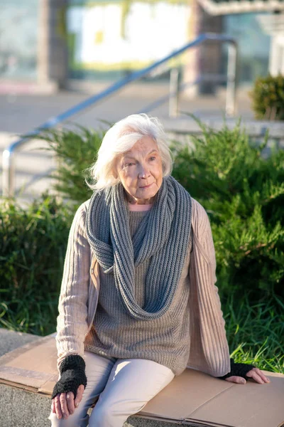 Poor aged woman sitting outside on her own — Stock Photo, Image